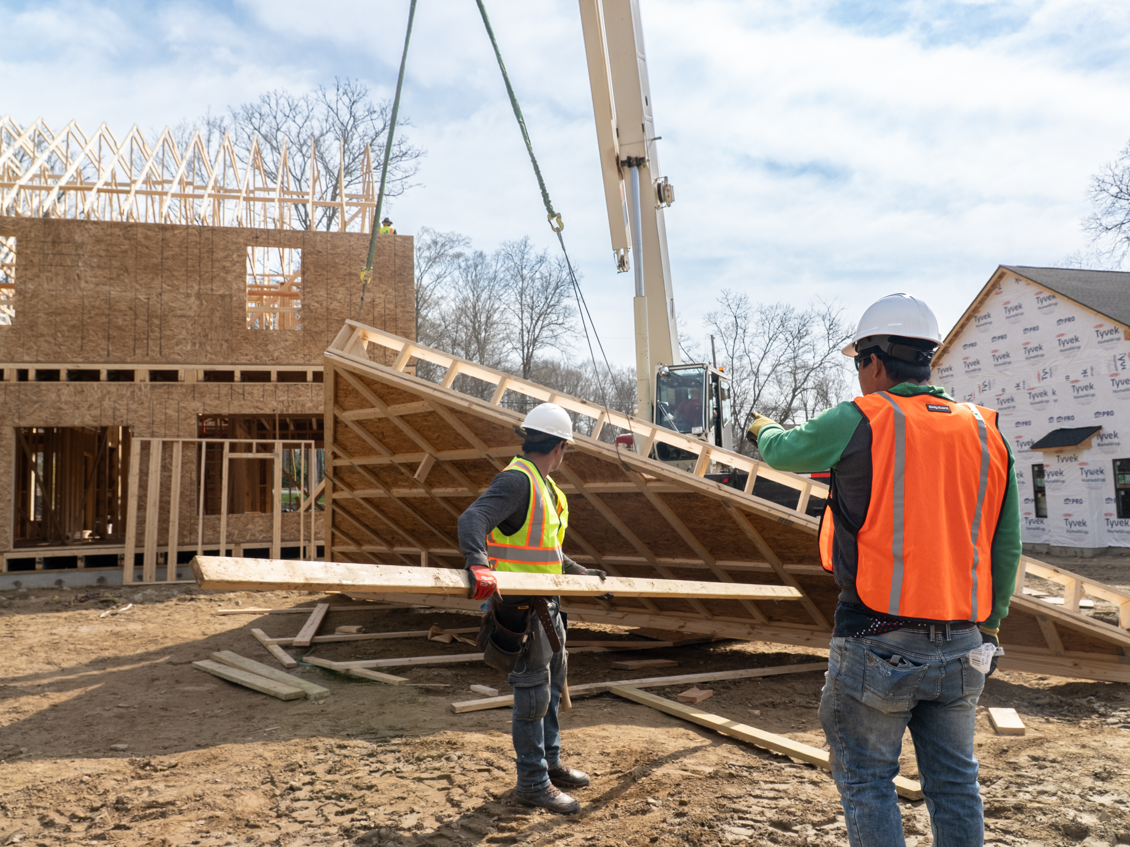 Construction crew coordinating panel installation on a multifamily job site